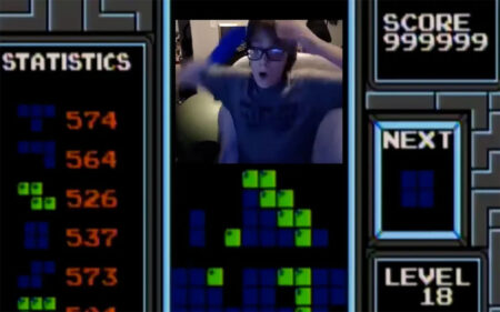 teenager reacts with excitement during a high-scoring game of Tetris displayed on the computer screen next to them