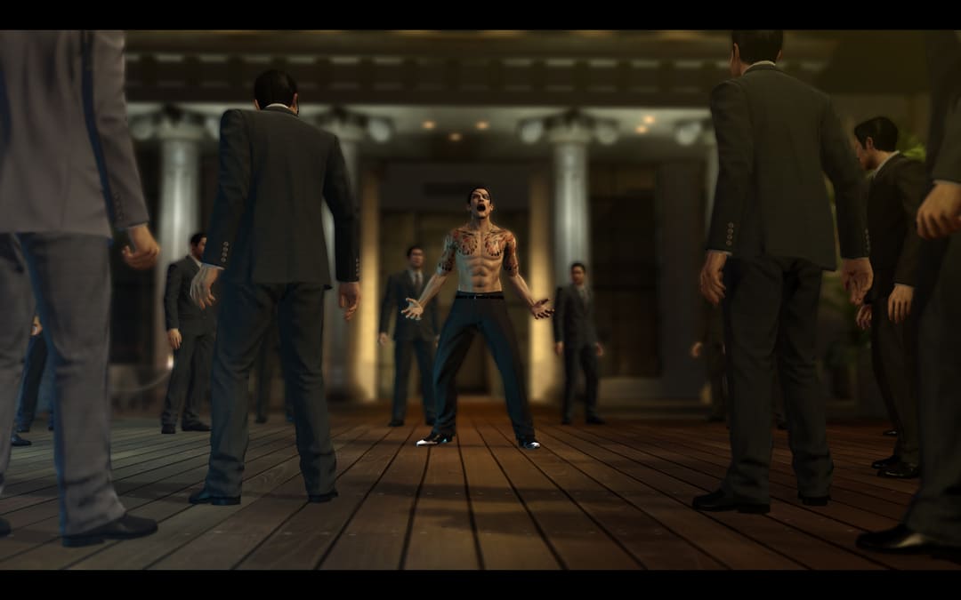 游戏Yakuza 0的屏幕截图显示了一个赤着拳的男人，有六包腹肌和一个穿着西装的男人中间的纹身尖叫