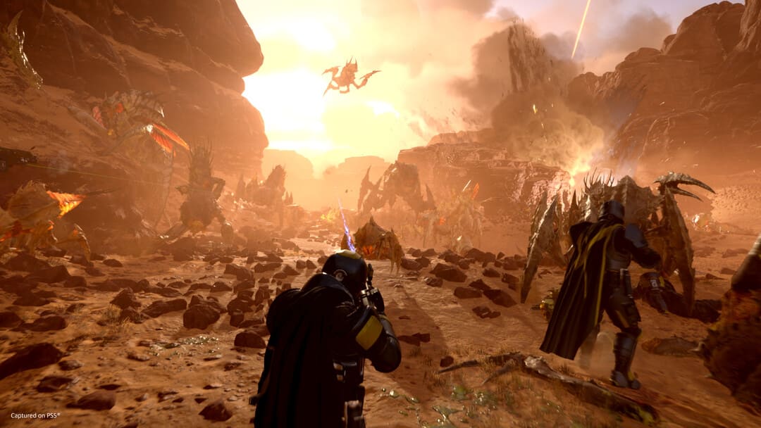 Game Helldivers 2的屏幕截图显示了对人类和昆虫之间类似火星的星球的攻击，后台爆炸